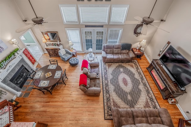 living area with a fireplace, french doors, wood finished floors, and ceiling fan
