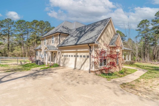 view of front of house featuring concrete driveway, cooling unit, a garage, fence, and a shingled roof