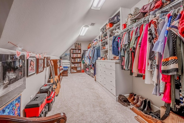 walk in closet with visible vents, carpet flooring, and lofted ceiling