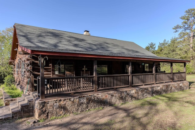 208 Mountain Dr, Perryville, AR 72126 - view of front facade with roof with shingles, log exterior, a chimney, and covered porch
