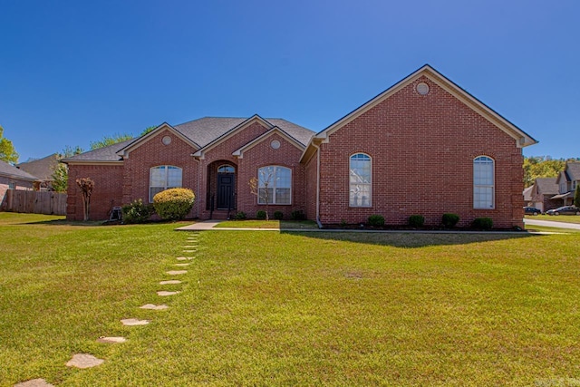 view of front of home with a front yard, fence, and brick siding