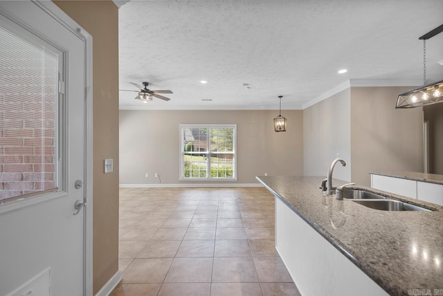 kitchen with crown molding, light tile patterned floors, a sink, and a textured ceiling