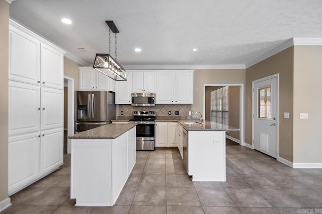 kitchen featuring crown molding, a peninsula, appliances with stainless steel finishes, a sink, and backsplash