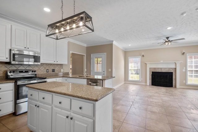 kitchen featuring ceiling fan, ornamental molding, a center island, appliances with stainless steel finishes, and decorative backsplash