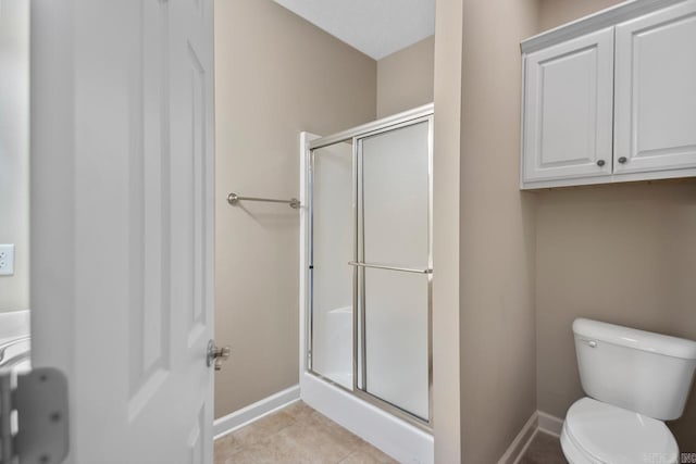 bathroom with a shower stall, tile patterned floors, baseboards, and toilet