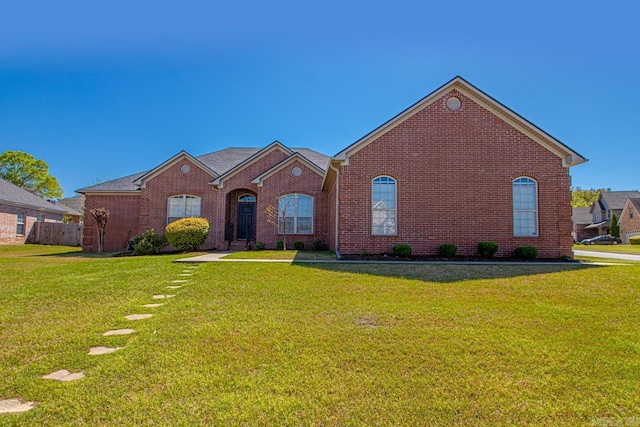 single story home featuring brick siding, a front yard, and fence