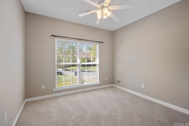 carpeted empty room with a textured ceiling, ceiling fan, and baseboards