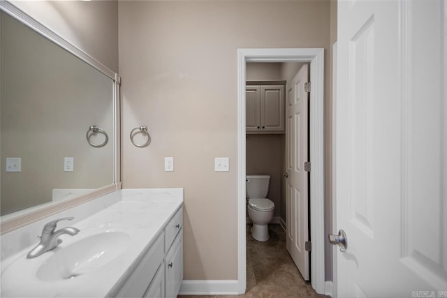 bathroom featuring toilet, tile patterned floors, vanity, and baseboards