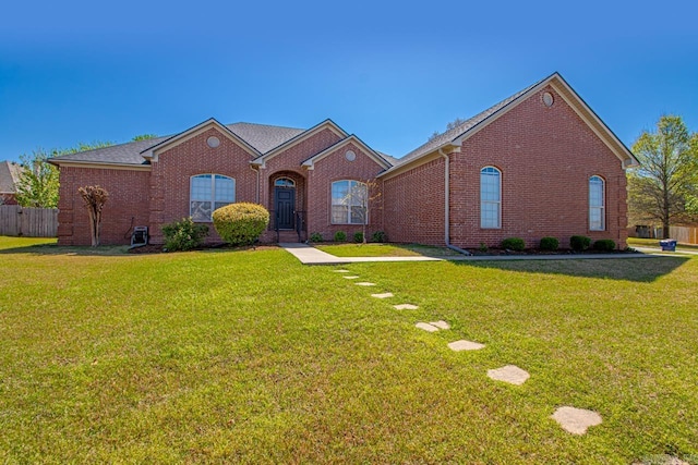 view of front facade featuring a front yard, brick siding, and fence