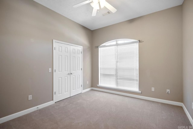 unfurnished room with carpet flooring, baseboards, and a ceiling fan