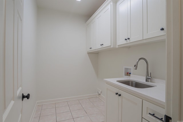 laundry area with hookup for a washing machine, light tile patterned flooring, a sink, baseboards, and cabinet space