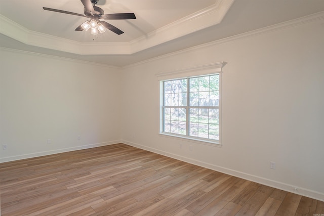 spare room featuring ornamental molding, a tray ceiling, light wood-type flooring, and a ceiling fan