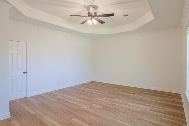 spare room featuring visible vents, ceiling fan, crown molding, a tray ceiling, and light wood finished floors