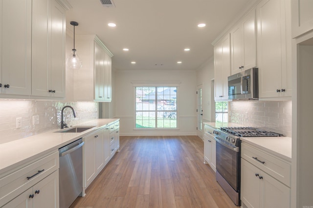 kitchen featuring light wood-type flooring, white cabinetry, light countertops, a sink, and stainless steel appliances