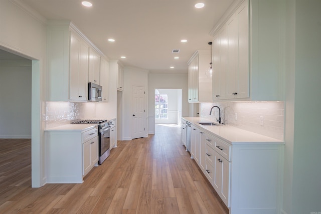 kitchen featuring light wood-type flooring, light countertops, white cabinetry, appliances with stainless steel finishes, and a sink