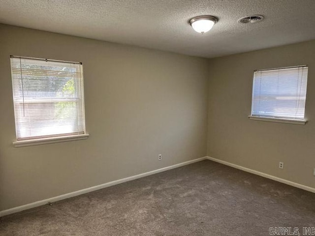 spare room featuring carpet, visible vents, baseboards, and a textured ceiling