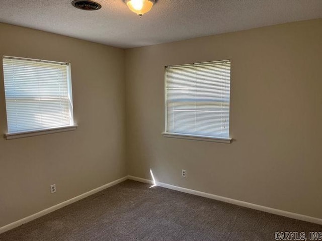 spare room featuring dark carpet, baseboards, and a textured ceiling