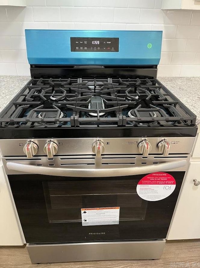 details featuring backsplash and stainless steel range with gas stovetop