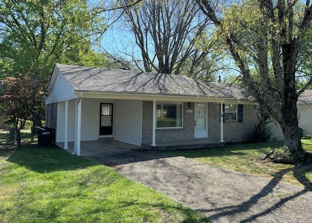 ranch-style home with a front yard, brick siding, an attached carport, and driveway