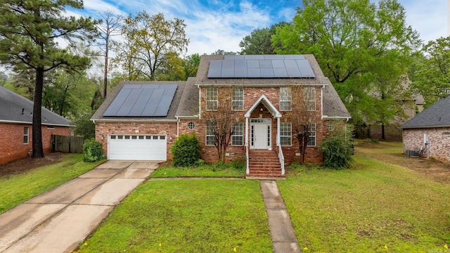 view of front facade featuring brick siding, fence, solar panels, a front lawn, and concrete driveway