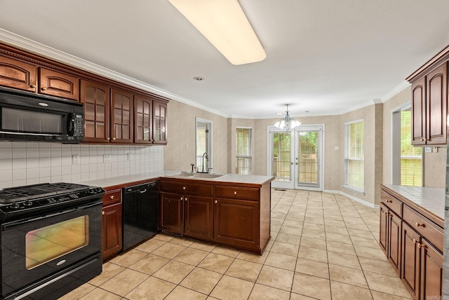 kitchen with tile countertops, a peninsula, black appliances, a chandelier, and a sink