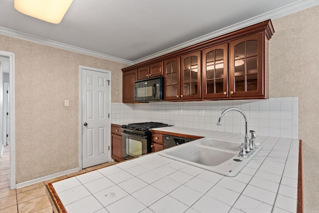 kitchen featuring tile counters, glass insert cabinets, crown molding, black appliances, and a sink