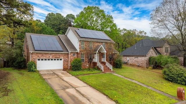 view of front facade featuring roof mounted solar panels, roof with shingles, a front lawn, brick siding, and driveway