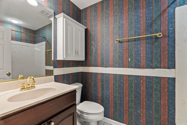 bathroom featuring visible vents, walk in shower, toilet, vanity, and wallpapered walls