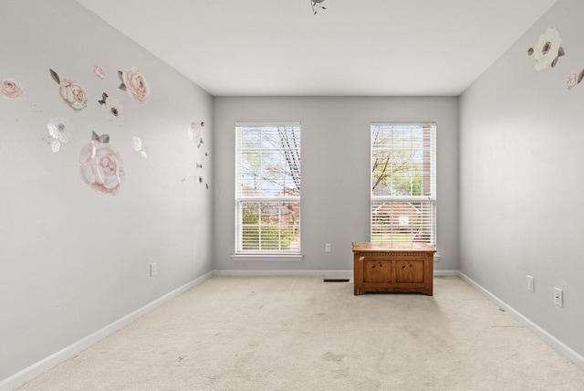 unfurnished room with visible vents, light colored carpet, and baseboards