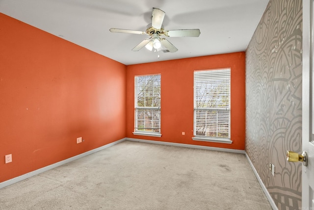 spare room with baseboards, ceiling fan, and carpet