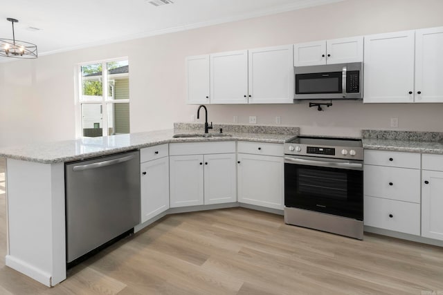 kitchen with a peninsula, crown molding, stainless steel appliances, light wood finished floors, and a sink