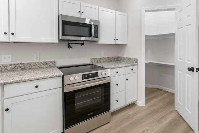 kitchen with white cabinets, light wood-style flooring, and appliances with stainless steel finishes