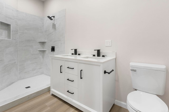 full bathroom with a sink, toilet, tiled shower, and wood finished floors
