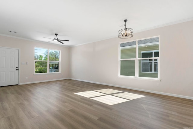 interior space with baseboards, crown molding, visible vents, ceiling fan with notable chandelier, and wood finished floors