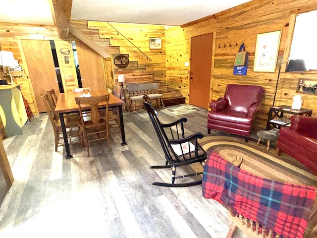 dining room with wood walls, stairway, and wood finished floors
