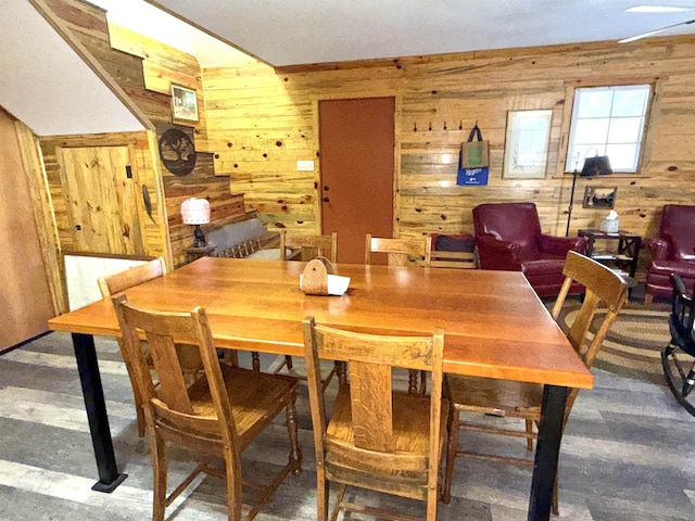 dining space with wooden walls, wood finished floors, and stairs