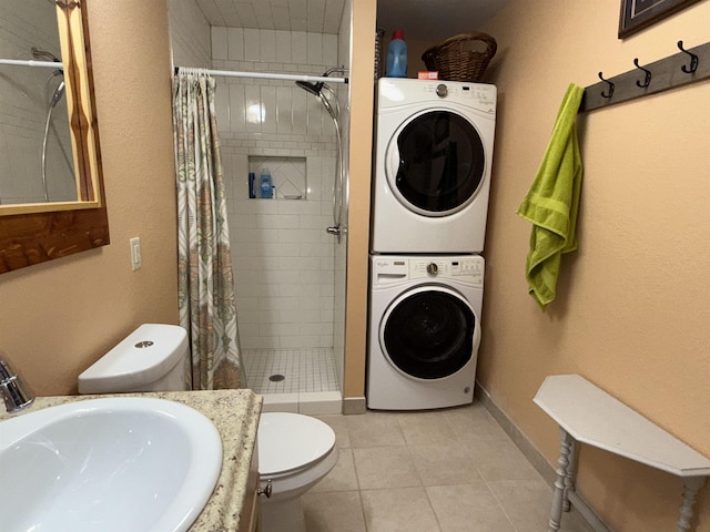 bathroom featuring stacked washer and dryer, toilet, a tile shower, and a sink