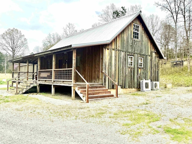 view of front of home featuring board and batten siding, ac unit, a porch, and metal roof