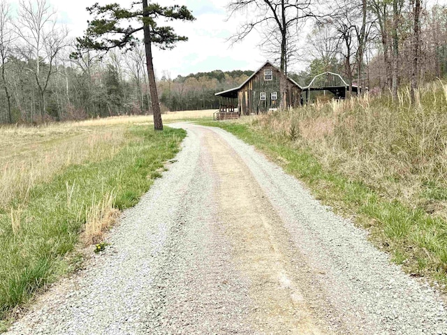 view of road with a barn and a view of trees