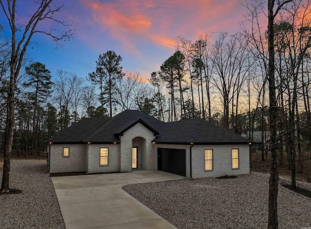 view of front of home featuring roof with shingles, a garage, and concrete driveway