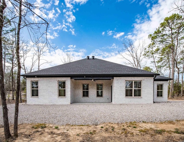 back of house featuring brick siding, ceiling fan, and roof with shingles