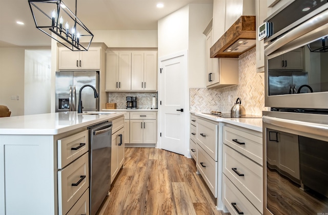 kitchen featuring decorative backsplash, appliances with stainless steel finishes, custom range hood, and light countertops