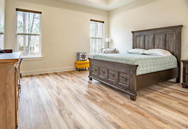 bedroom featuring light wood finished floors and baseboards