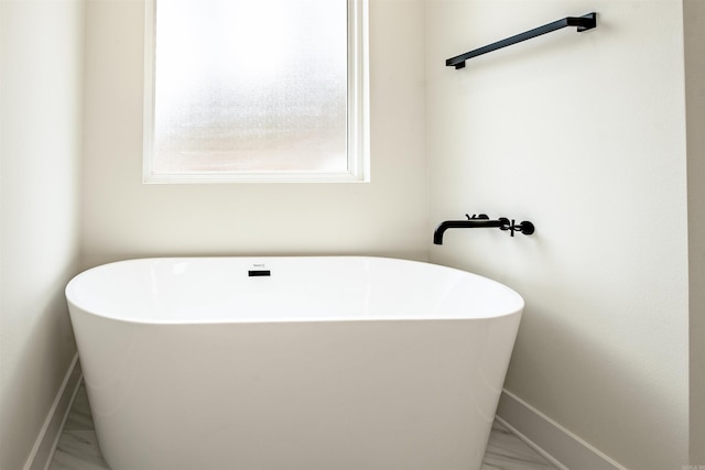 bathroom featuring a freestanding tub and baseboards