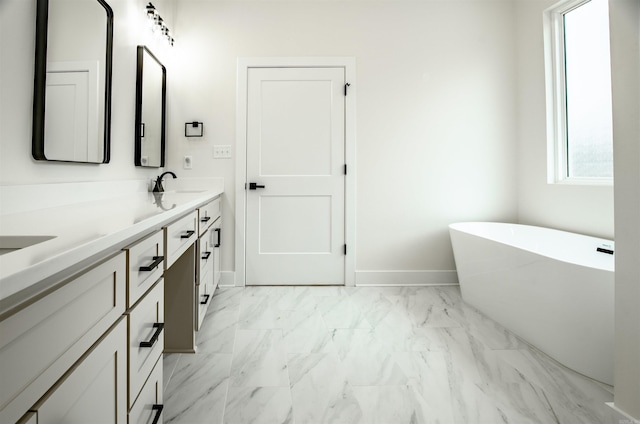 full bath featuring a sink, double vanity, marble finish floor, and a soaking tub