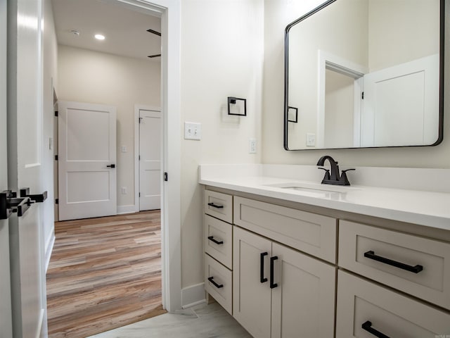 bathroom featuring recessed lighting, vanity, baseboards, and wood finished floors