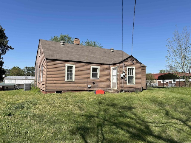 604 E Church St, Morrilton, AR 72110 - back of property with central air condition unit, a yard, a shingled roof, and a chimney