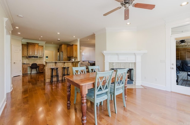 3015 Woodsgate, Little Rock, AR 72211 - dining room featuring a fireplace, light wood-style flooring, ornamental molding, and ceiling fan