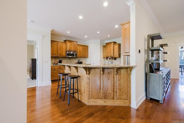 3015 Woodsgate, Little Rock, AR 72211 - kitchen with stainless steel microwave, tasteful backsplash, a peninsula, light stone countertops, and brown cabinetry