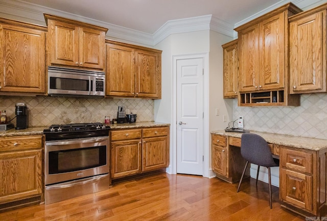 3015 Woodsgate, Little Rock, AR 72211 - kitchen with built in desk, ornamental molding, brown cabinetry, appliances with stainless steel finishes, and light wood finished floors